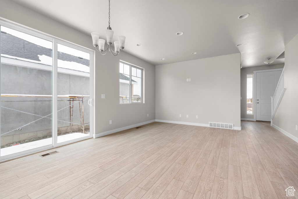 Empty room with a chandelier and light hardwood / wood-style flooring