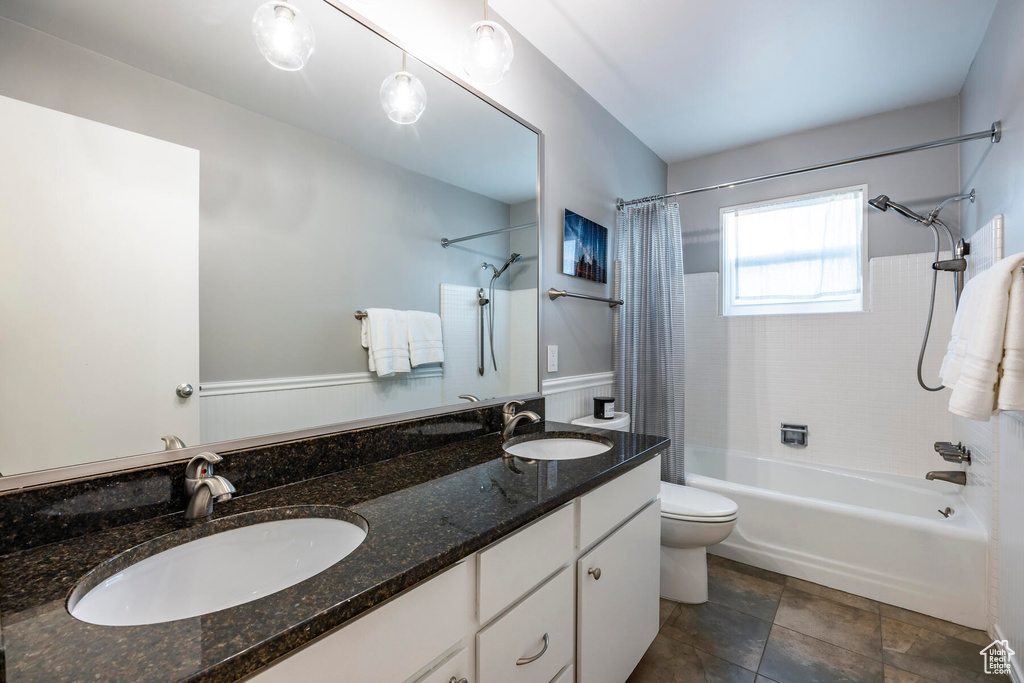 Full bathroom featuring dual bowl vanity, shower / bath combination with curtain, tile floors, and toilet