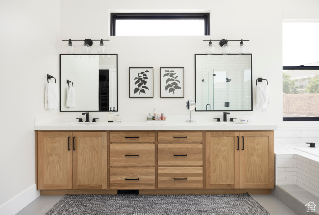Bathroom with dual bowl vanity, tile flooring, and tiled tub