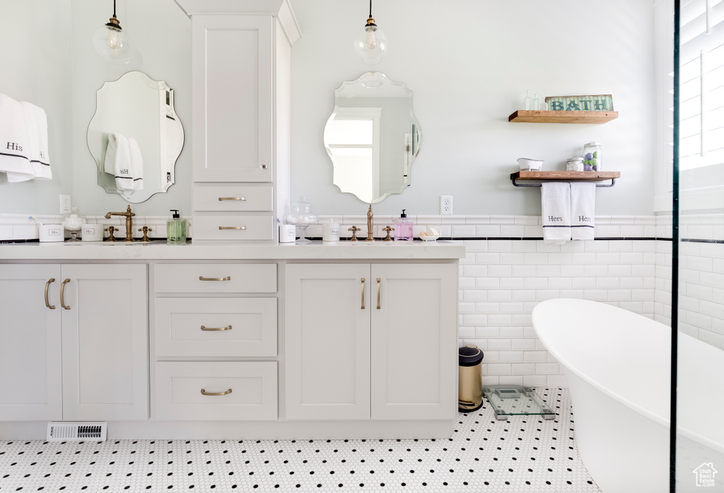 Bathroom featuring double sink vanity, tile walls, tile flooring, and a bathtub