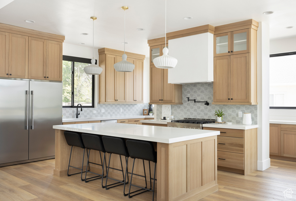 Kitchen featuring a center island, light hardwood / wood-style flooring, pendant lighting, and stainless steel built in fridge