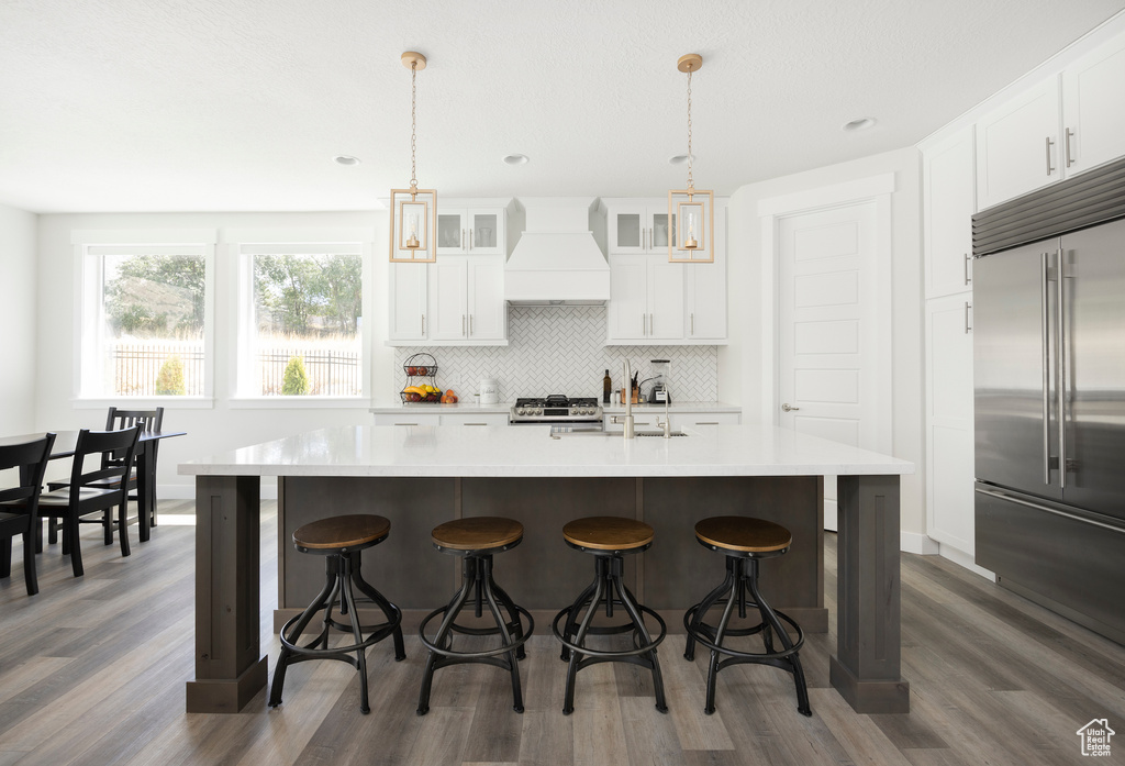 Kitchen with decorative light fixtures, dark hardwood / wood-style floors, stainless steel appliances, and premium range hood