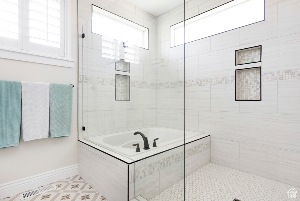 Bathroom with tiled tub, tile floors, and a wealth of natural light