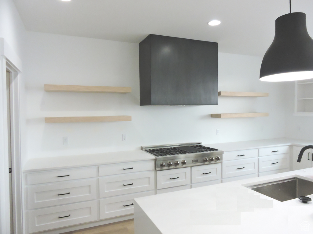 Kitchen featuring sink, hanging light fixtures, stainless steel gas cooktop, white cabinets, and light wood-type flooring