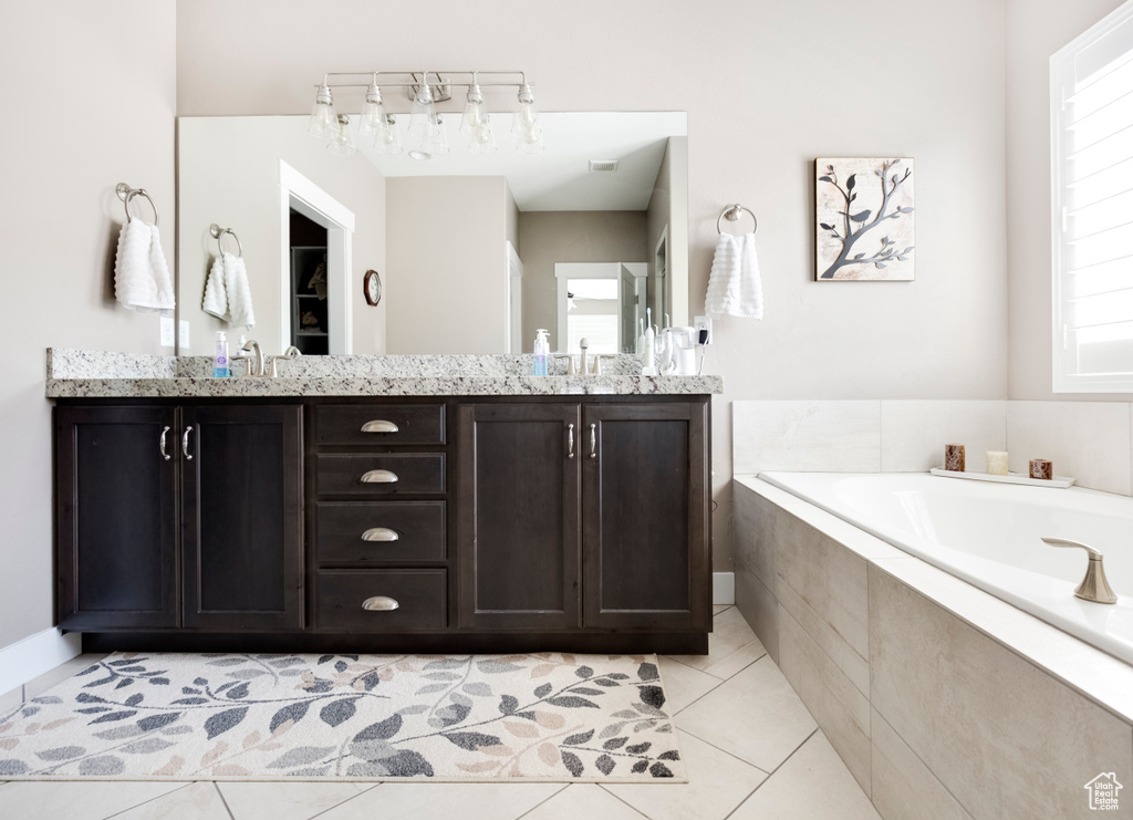 Bathroom featuring tiled bath, tile floors, and dual vanity