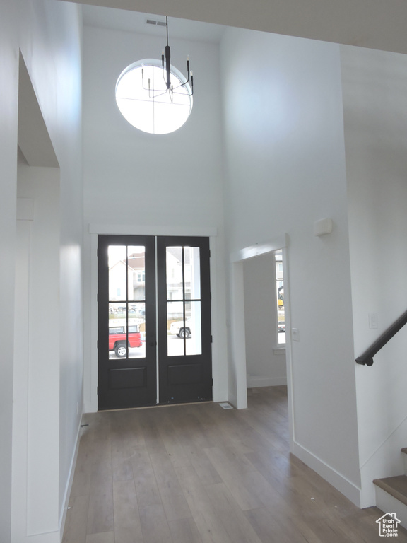 Foyer entrance with a high ceiling, light hardwood / wood-style flooring, and french doors