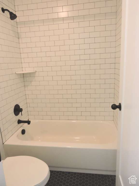 Bathroom featuring tiled shower / bath combo, tile floors, and toilet