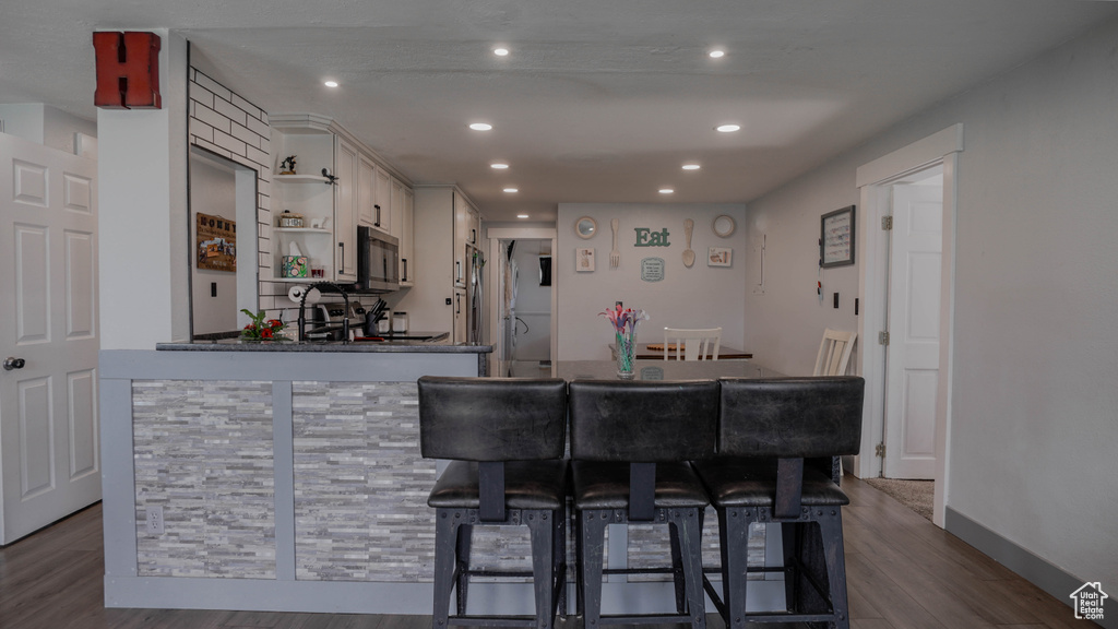 Kitchen with white cabinets, a kitchen breakfast bar, kitchen peninsula, and dark hardwood / wood-style flooring