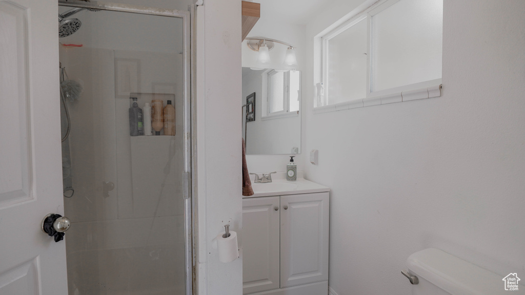 Bathroom featuring vanity, a shower with door, and toilet