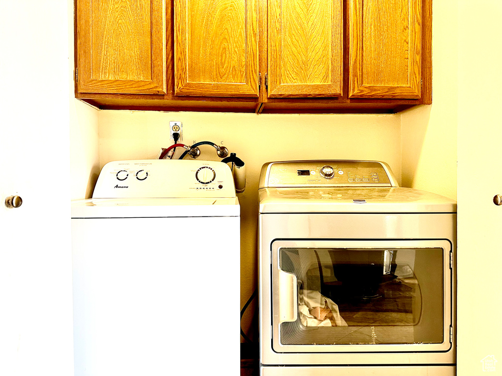 Clothes washing area with cabinets, washer and clothes dryer, and washer hookup