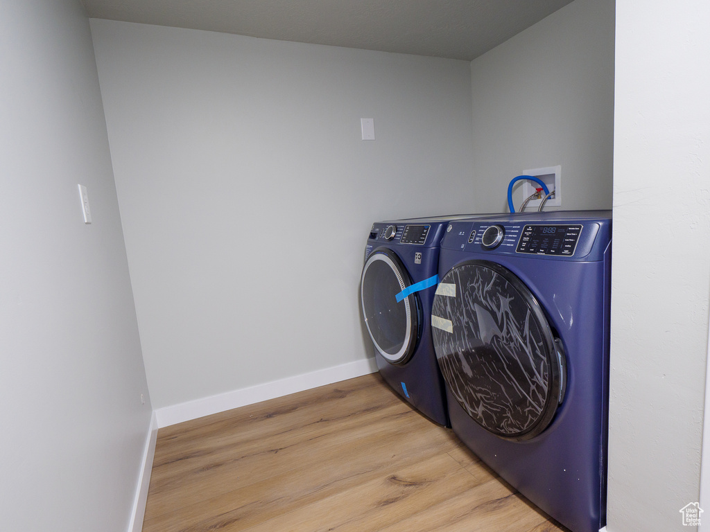 Clothes washing area featuring washer hookup, washer and dryer, and light hardwood / wood-style flooring