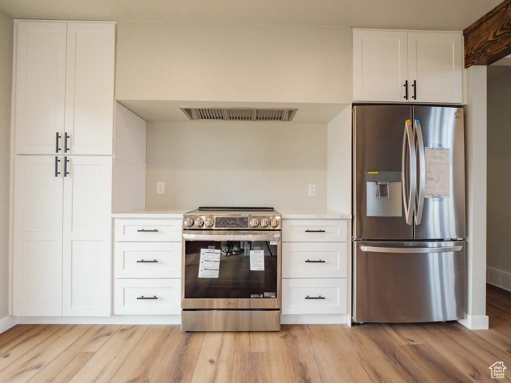 Kitchen featuring white cabinets, light wood-type flooring, and appliances with stainless steel finishes