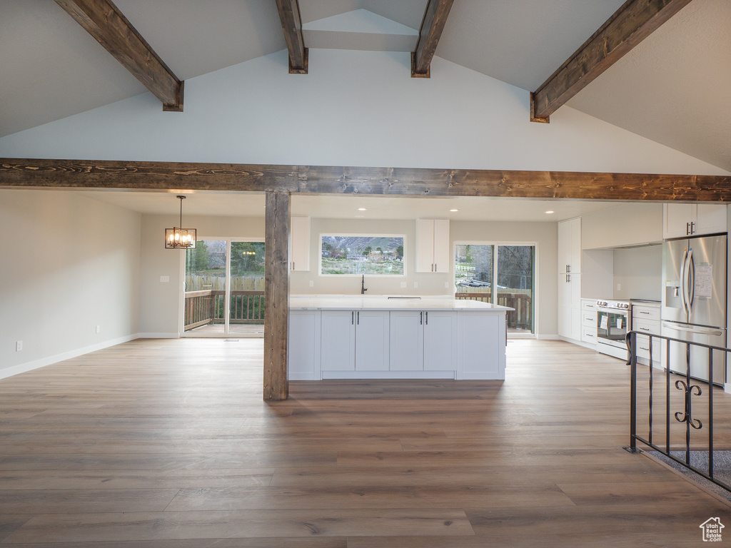 Kitchen featuring light wood-type flooring, stainless steel refrigerator with ice dispenser, white cabinetry, and lofted ceiling with beams