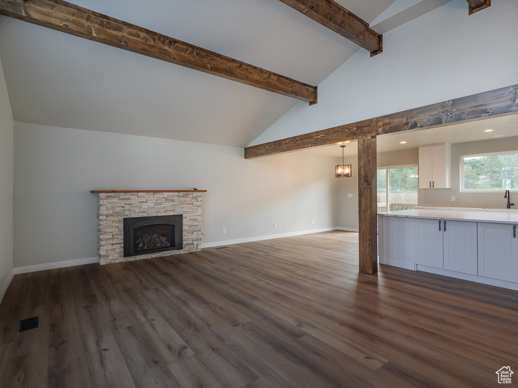 Unfurnished living room with lofted ceiling with beams, dark hardwood / wood-style floors, and a fireplace