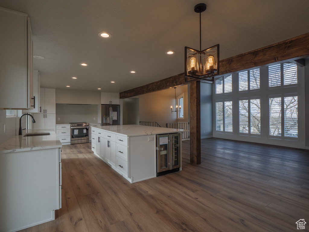 Kitchen featuring pendant lighting, a center island, appliances with stainless steel finishes, white cabinets, and dark hardwood / wood-style floors