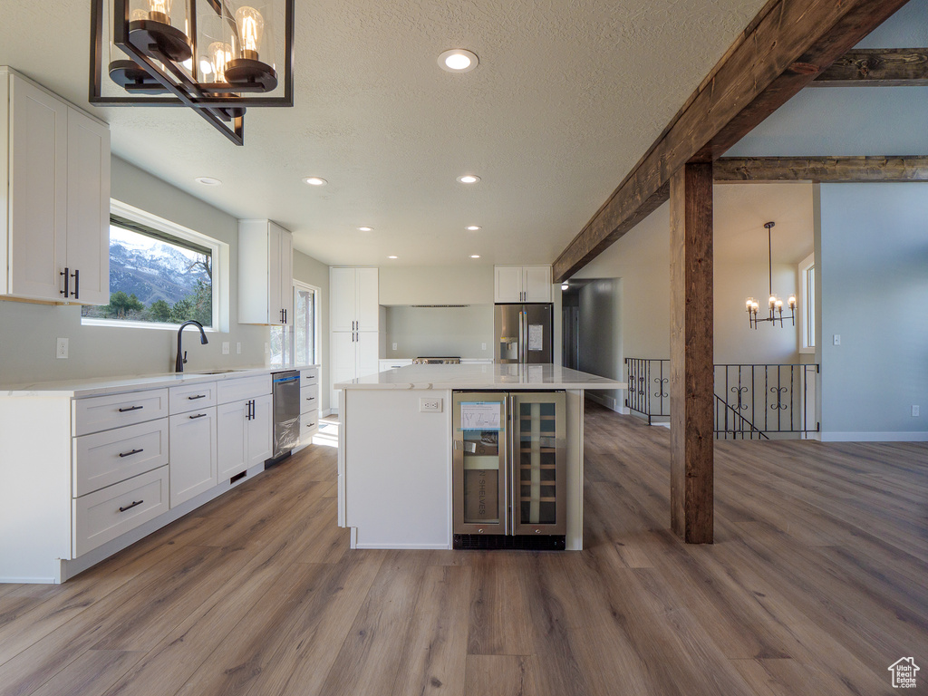 Kitchen featuring pendant lighting, a center island, hardwood / wood-style flooring, white cabinetry, and stainless steel fridge with ice dispenser