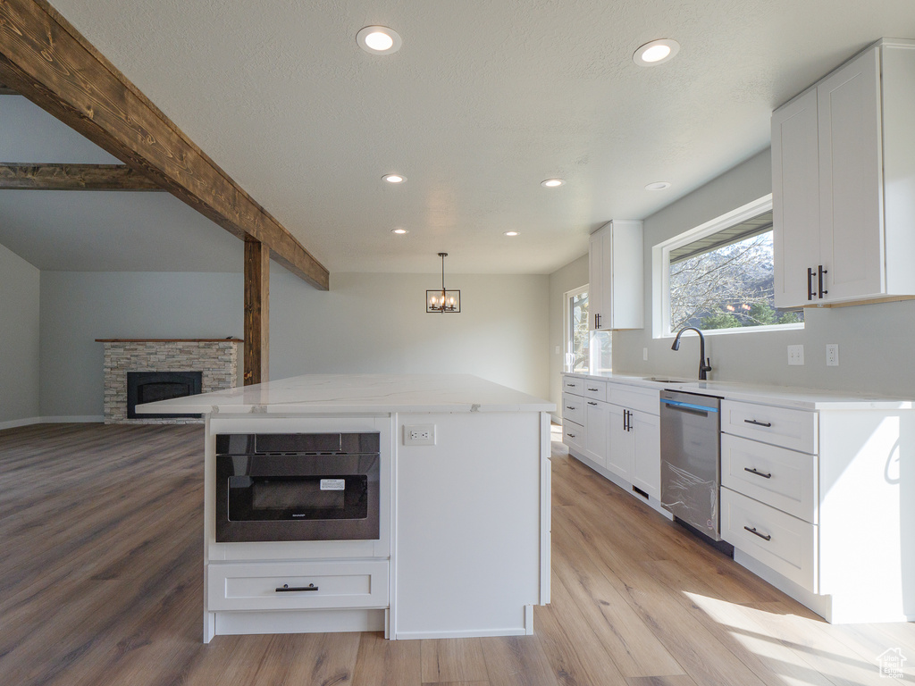 Kitchen featuring a kitchen island, decorative light fixtures, white cabinets, and dishwasher