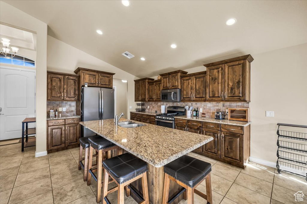 Kitchen featuring an inviting chandelier, appliances with stainless steel finishes, backsplash, and a breakfast bar area