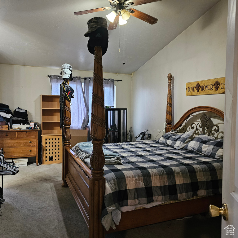 Bedroom with dark colored carpet, lofted ceiling, and ceiling fan