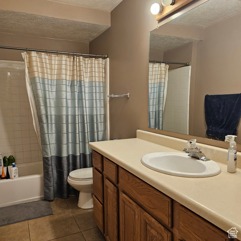 Full bathroom with toilet, shower / tub combo with curtain, vanity, a textured ceiling, and tile floors