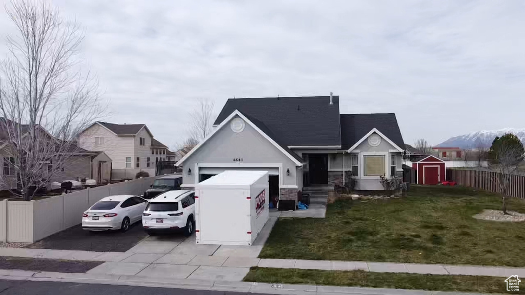 View of front facade featuring a front yard, a storage unit, and a garage