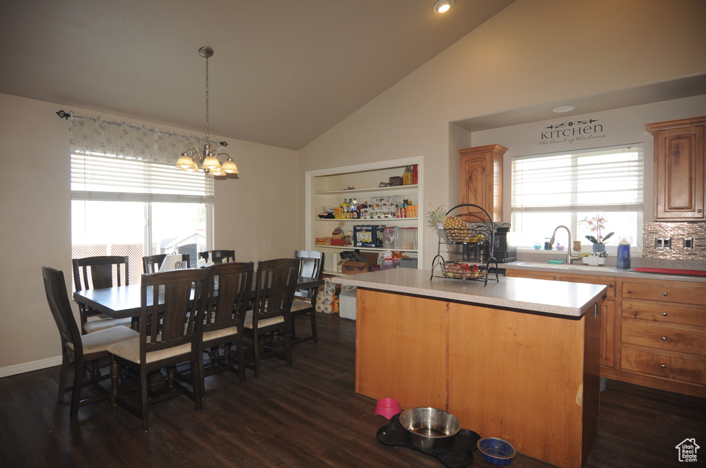 Kitchen featuring dark hardwood / wood-style floors, a chandelier, a kitchen island, tasteful backsplash, and pendant lighting