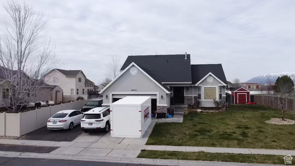 View of front of home with a front lawn, a storage unit, and a garage