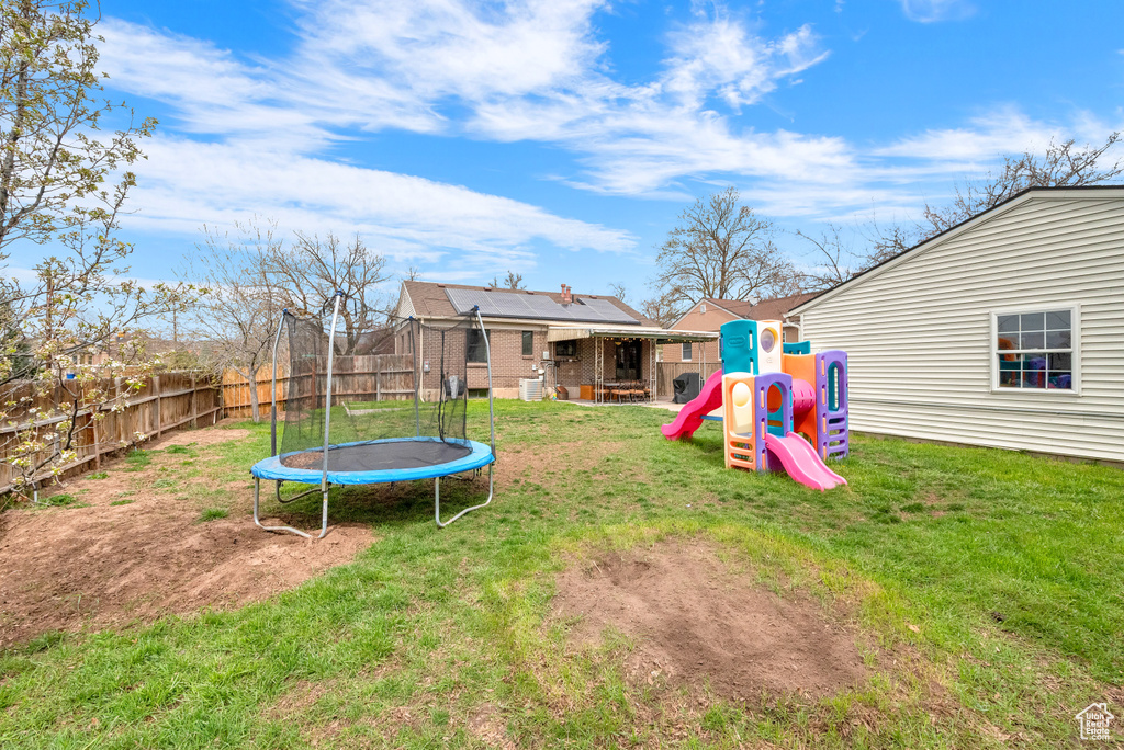 View of yard featuring a trampoline and a playground