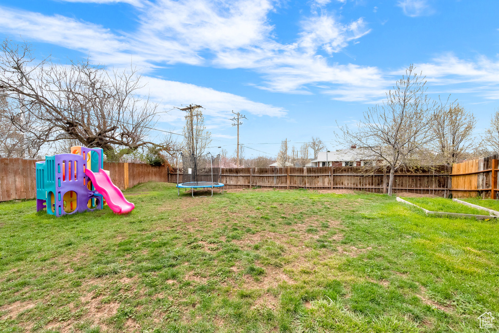 View of yard featuring a playground and a trampoline