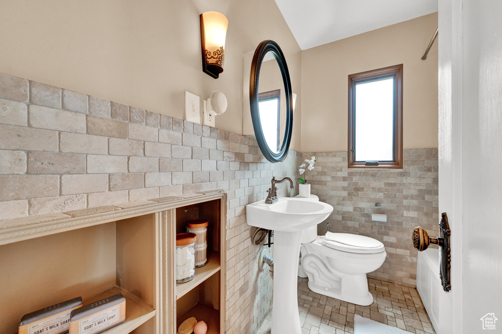 Bathroom featuring tile walls, tile floors, backsplash, shower / washtub combination, and toilet