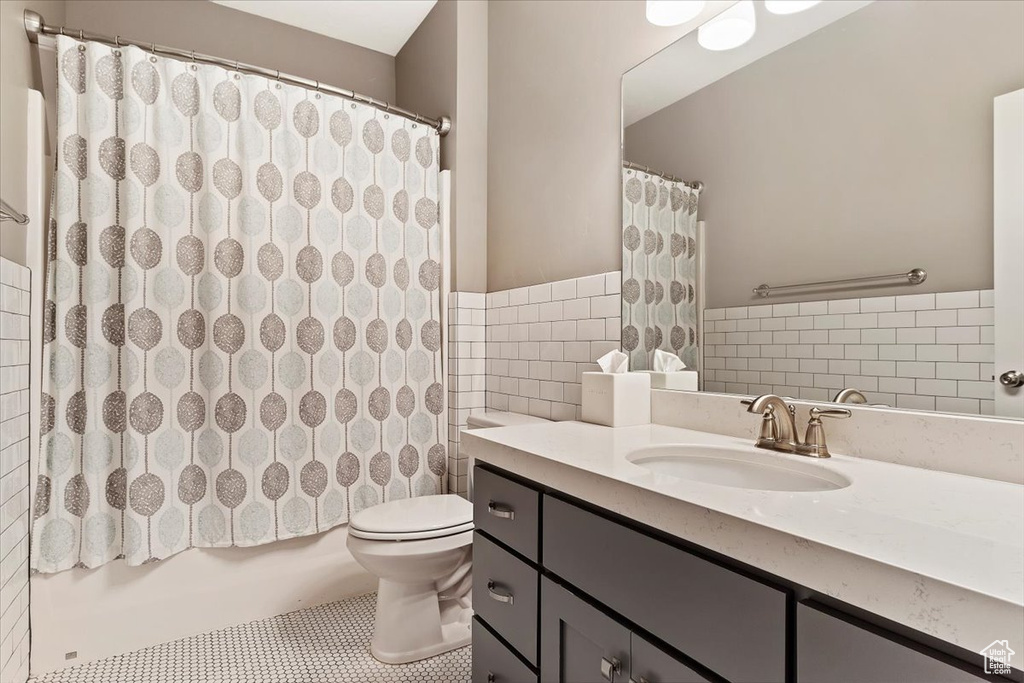 Full bathroom featuring tile walls, shower / bathtub combination with curtain, tile flooring, toilet, and large vanity
