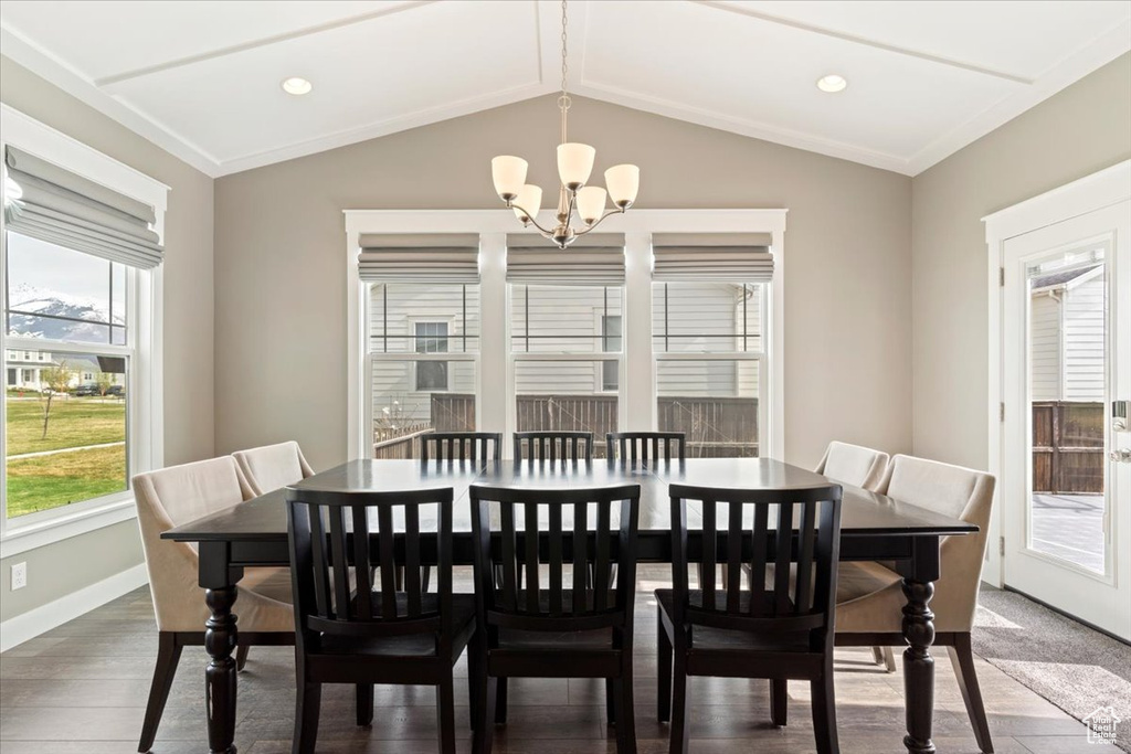 Dining room with an inviting chandelier, crown molding, dark hardwood / wood-style floors, and vaulted ceiling