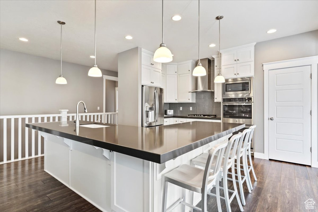 Kitchen featuring stainless steel appliances, a kitchen bar, and decorative light fixtures