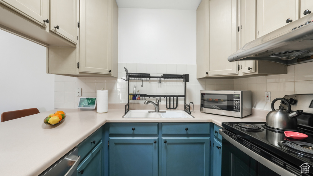 Kitchen featuring white cabinets, blue cabinetry, range, and backsplash