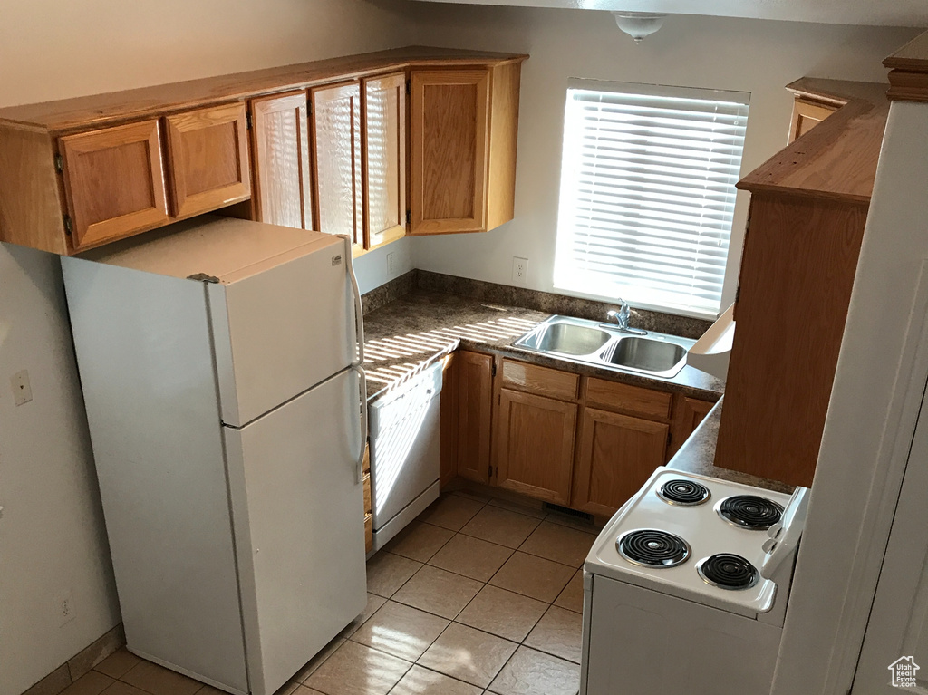 Kitchen featuring light tile floors, white appliances, and sink