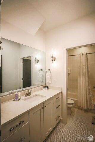Full bathroom featuring toilet, shower / tub combo, tile floors, and vanity