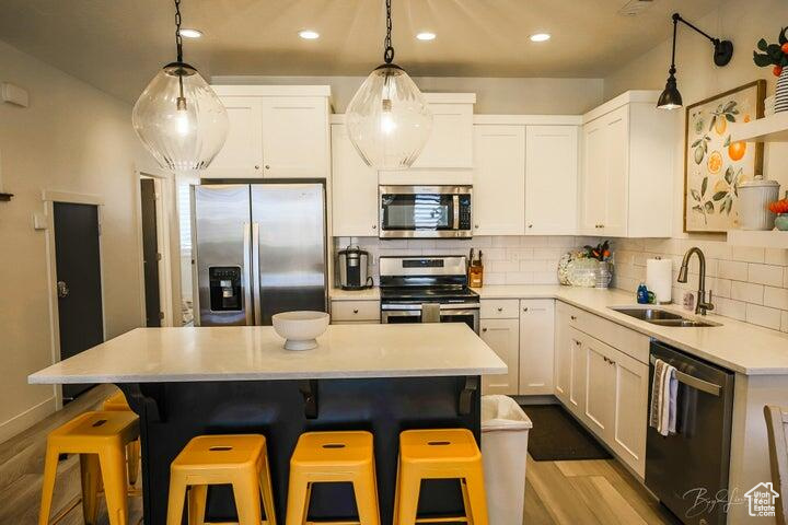 Kitchen with stainless steel appliances, a kitchen island, white cabinetry, and a breakfast bar