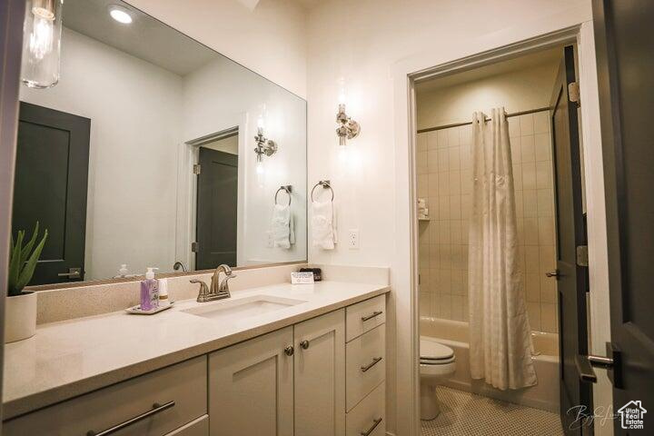 Full bathroom with toilet, shower / tub combo with curtain, and vanity