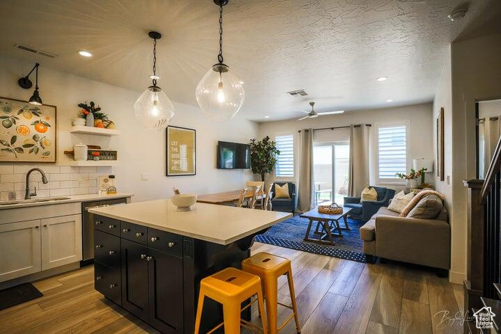 Kitchen with ceiling fan, sink, light hardwood / wood-style flooring, and tasteful backsplash