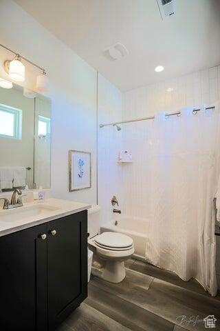 Full bathroom featuring shower / tub combo, vanity, wood-type flooring, and toilet