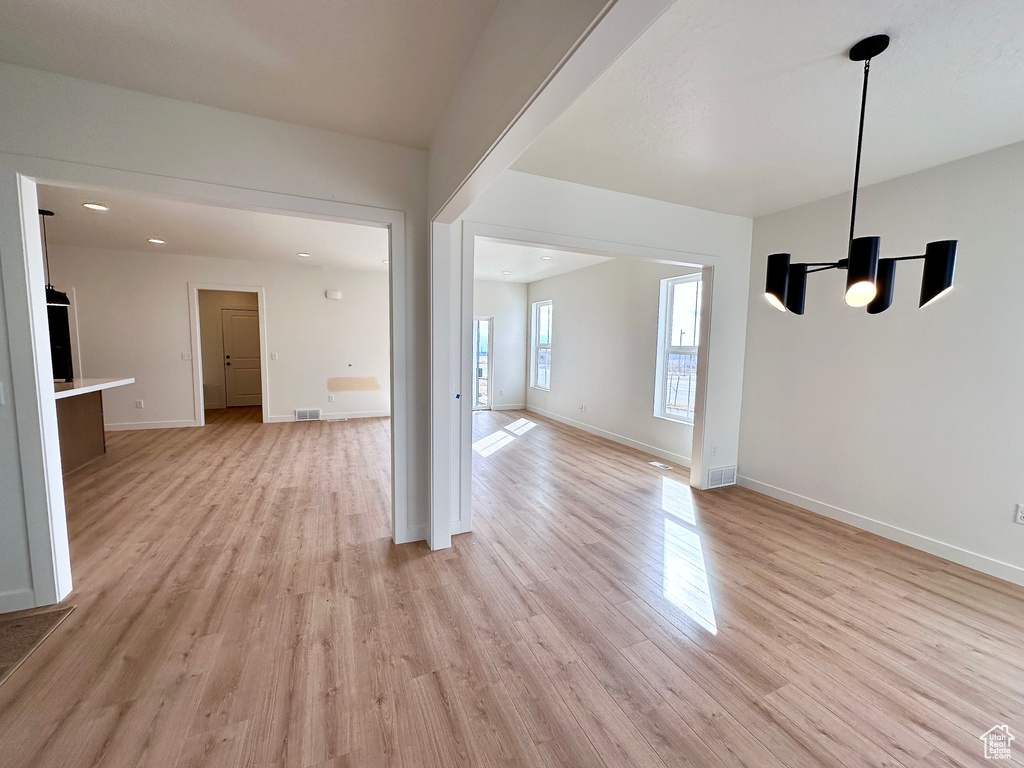 Empty room with a notable chandelier and light hardwood / wood-style floors
