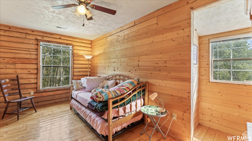 Bedroom featuring rustic walls, a textured ceiling, ceiling fan, and light wood-type flooring