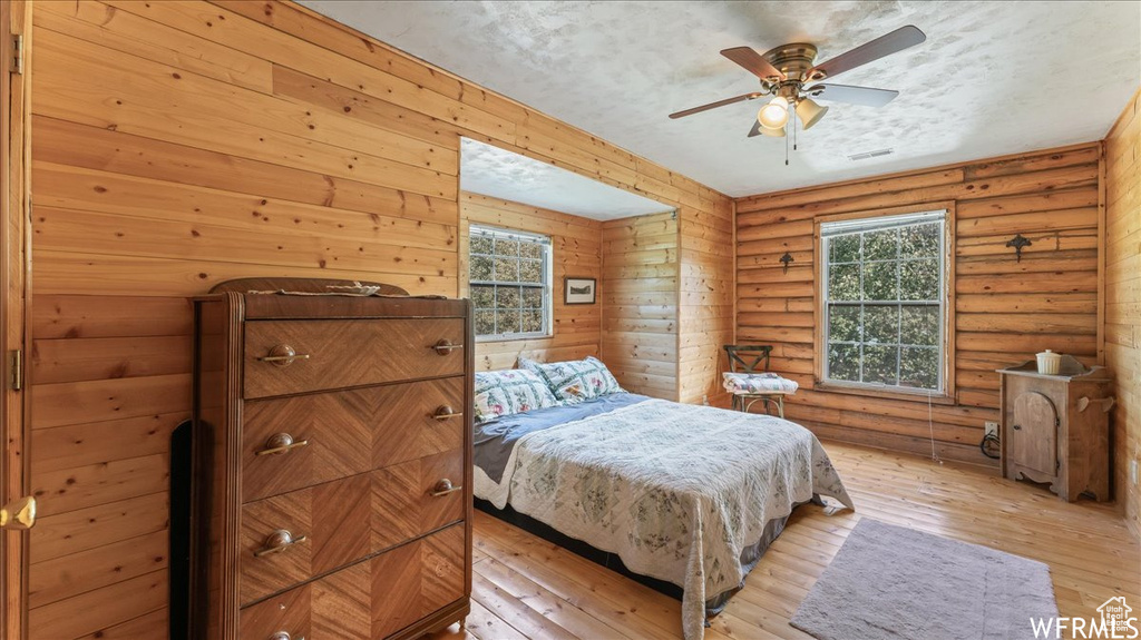 Bedroom featuring log walls, ceiling fan, and light wood-type flooring