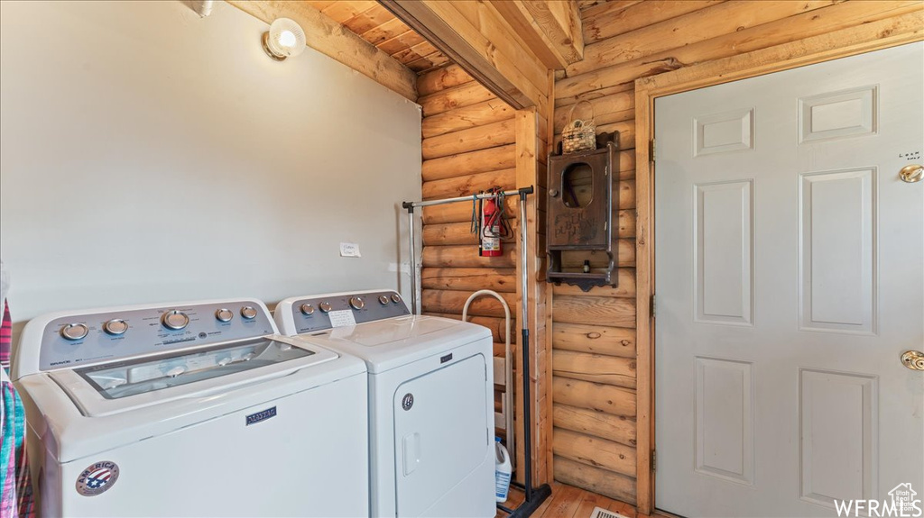 Clothes washing area with wooden ceiling, independent washer and dryer, light wood-type flooring, and rustic walls