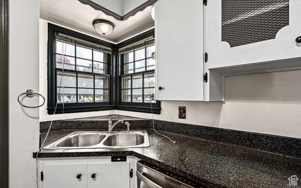 Kitchen featuring sink, dark stone countertops, and white cabinetry