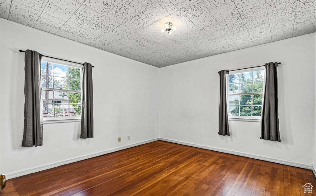 Unfurnished room with a healthy amount of sunlight and dark wood-type flooring