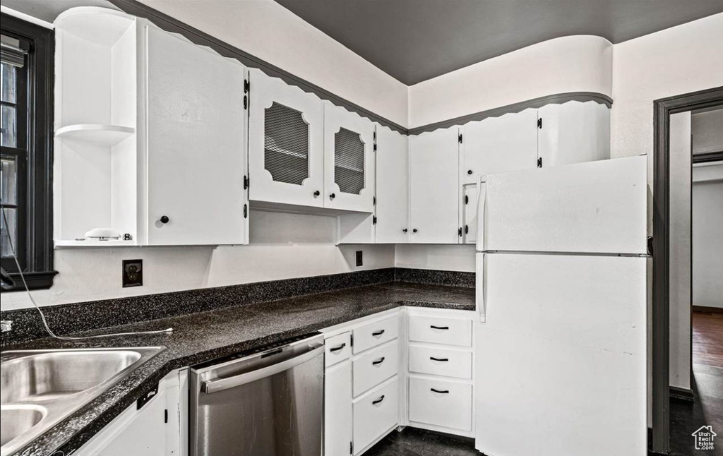 Kitchen with white refrigerator, white cabinets, dark wood-type flooring, and dishwasher