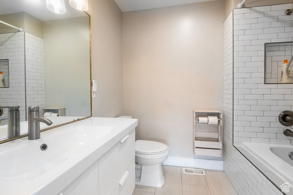 Full bathroom featuring toilet, tile floors, tiled shower / bath combo, and vanity with extensive cabinet space