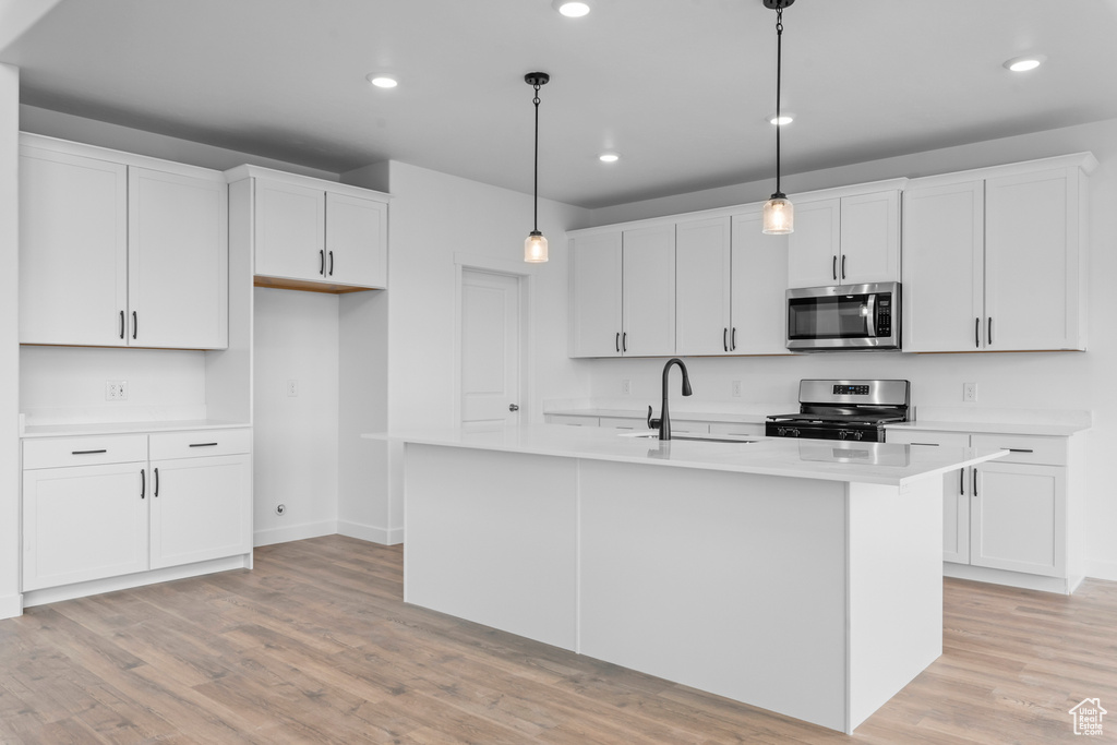 Kitchen with pendant lighting, white cabinets, appliances with stainless steel finishes, and sink