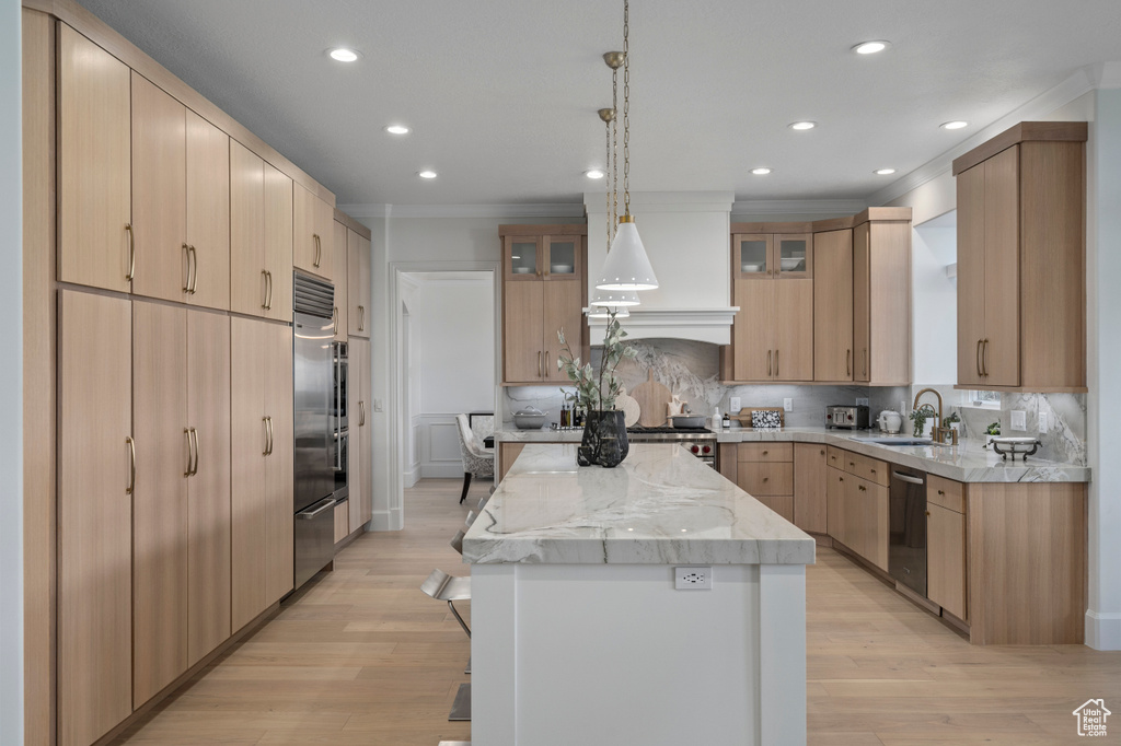 Kitchen with a kitchen island, backsplash, light wood-type flooring, and pendant lighting